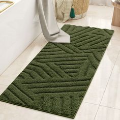 a bathroom with a green rug on the floor and a white bathtub in the background