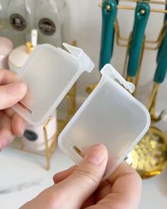 a person holding two plastic containers in front of a counter with other items on it