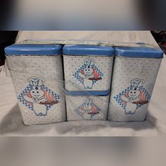 four blue and white tins with cartoon characters on them are sitting on a table