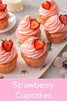 strawberry cupcakes with pink frosting and strawberries on top, sitting on a plate