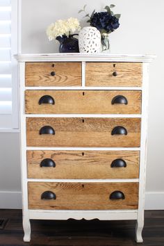 a white dresser with wooden drawers and black knobs