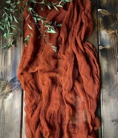 an orange cloth with some green leaves on top of wooden planked floor next to it