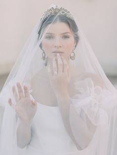 a woman wearing a veil and holding her hand up to her mouth