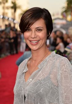 a woman smiling on the red carpet at an event