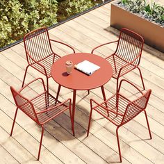 an outdoor table with four chairs and a laptop on top of it in the middle of a wooden deck