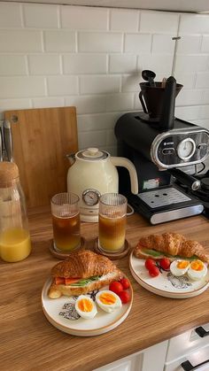 there are two plates with sandwiches on the counter next to coffee maker and toaster