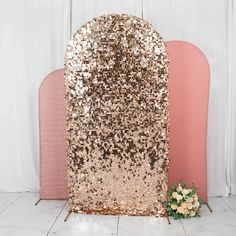 a pink and gold sequined chair next to a pink headboard in front of a white wall