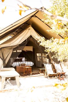 the inside of a tent with two chairs and a table in front of it,