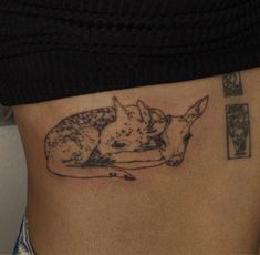 a small tattoo on the side of a woman's stomach depicting a fox and her cub