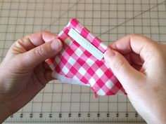 someone is making a small piece of paper with pink and white gingham fabric