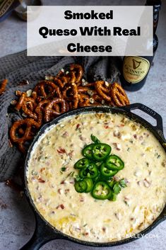 a skillet filled with cheese and green peppers next to pretzels