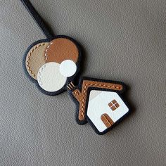 two luggage tags with houses on them sitting on a gray surface, one is brown and the other is white