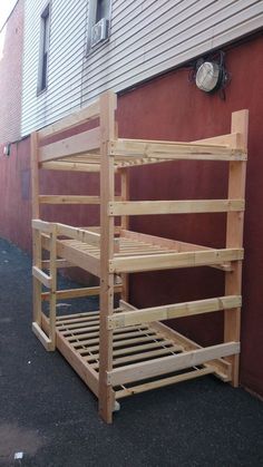 a wooden bunk bed sitting next to a red building