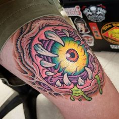 a colorful tattoo on the leg of a man with an eyeball in the center