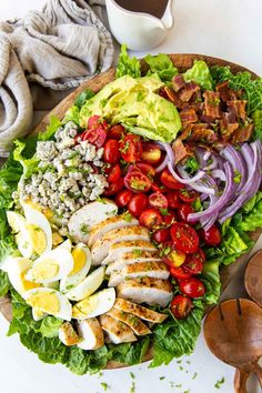 the classic cobb salad is loaded with chicken, tomatoes, lettuce, hard boiled eggs and avocado