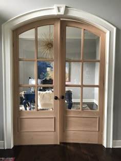 two wooden doors with glass on top of them in front of a wall and hardwood floor