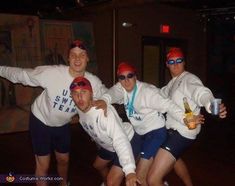 three men in white sweatshirts and blue shorts posing for a photo with beer bottles