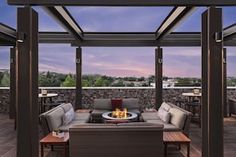 an outdoor living area with couches, tables and fire pit in the evening time