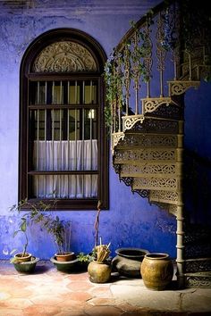 an old building with some pots and plants in front of a window on the outside