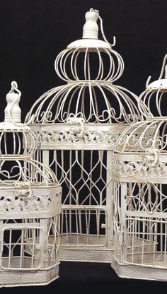 white birdcages with figurines sitting on top of them