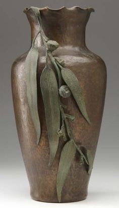 a brown vase with green leaves on it