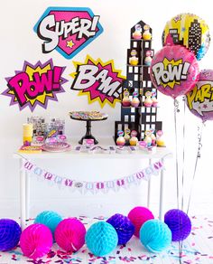 a table topped with lots of balloons next to a cake and confetti bar