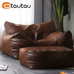 a brown leather chair sitting on top of a metal table next to a potted plant