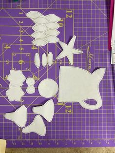 cut out pieces of paper sitting on top of a purple cutting mat next to scissors