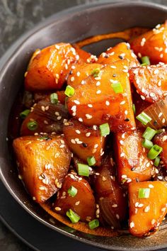 a bowl filled with cooked carrots and sesame seeds on top of a wooden spoon