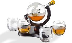 a set of four glasses and a decanter with a globe in it on a stand