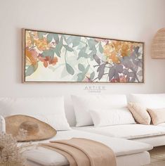 a living room with white couches and large painting on the wall above it's headboard