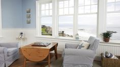 a living room filled with furniture next to a large window covered in white curtains and blue walls