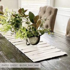 a wooden table topped with green plants and potted planters on top of it