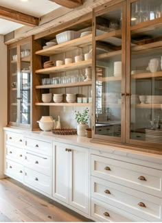 a kitchen with white cupboards and glass front cabinets in the center, filled with dishes