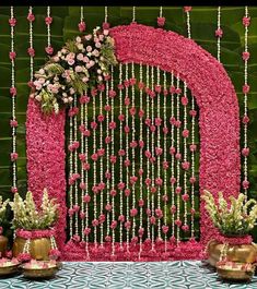 a pink and white wedding backdrop with flowers on the front, along with gold vases