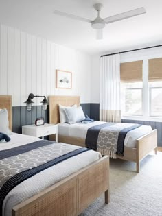 two beds in a room with white walls and blue accents on the headboard, one is made from wood