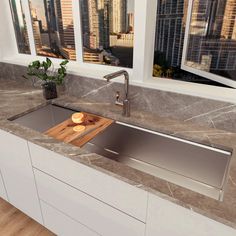 a kitchen sink with a cutting board on the counter top in front of large windows