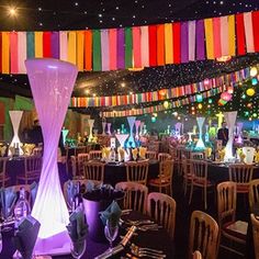 a banquet hall with tables and chairs covered in colorful streamers