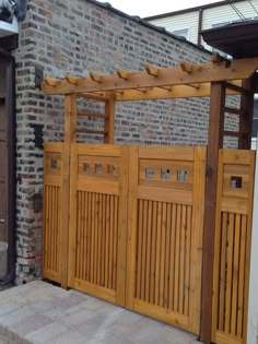 a large wooden gate in front of a brick building with a pergolated roof