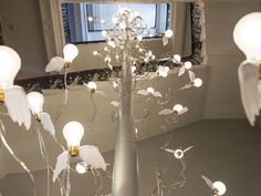 an artistic sculpture with white flowers and lights in front of a mirror on the floor