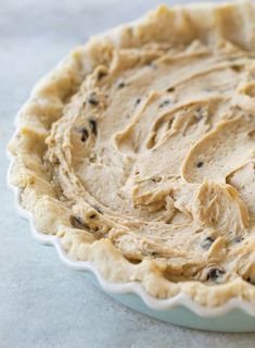 an unbaked pie crust in a white dish on top of a marble counter