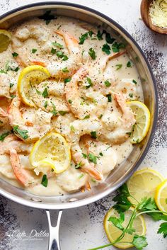 a pan filled with shrimp and lemons on top of a table