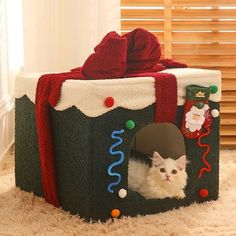 a white cat sitting in a christmas themed pet house with presents on the top and bottom