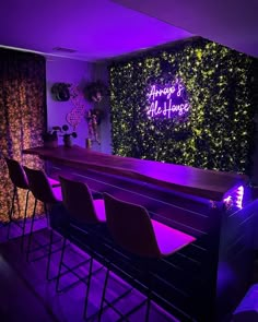 the bar is lit up with purple lights and has chairs around it, along with plants on the wall