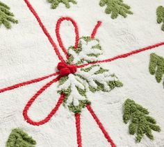 a white rug with green and red trimmings on top of it, decorated with snowflakes