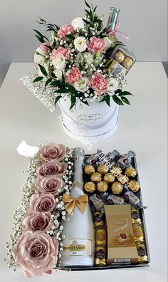 flowers, chocolates and champagne are arranged in a white hat box on a table