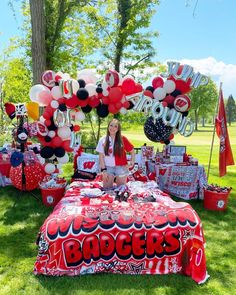 a woman sitting on top of a table covered in red and white balloons with the word badgers