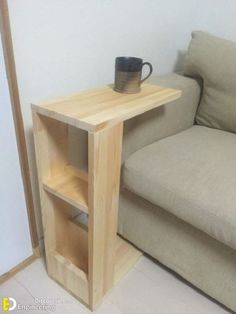 a small wooden table with a cup on it next to a couch and coffee mug