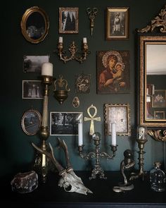 there are many pictures on the wall with candles in front of them and other decorations