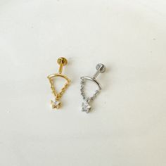 two pairs of gold and silver earrings on a white surface, one has a diamond in the middle